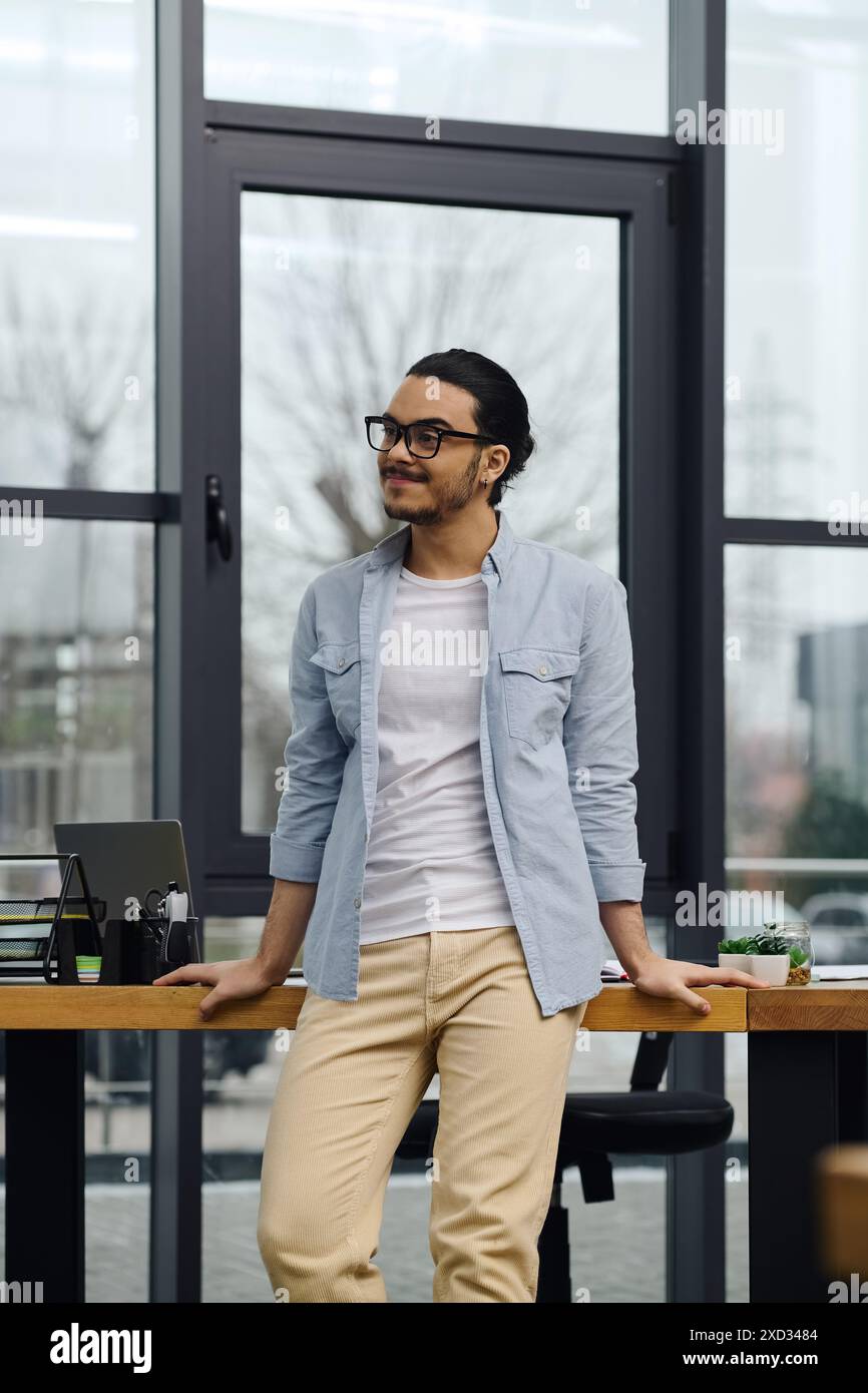 Un uomo in piedi con sicurezza a una scrivania elegante in un ufficio moderno. Foto Stock