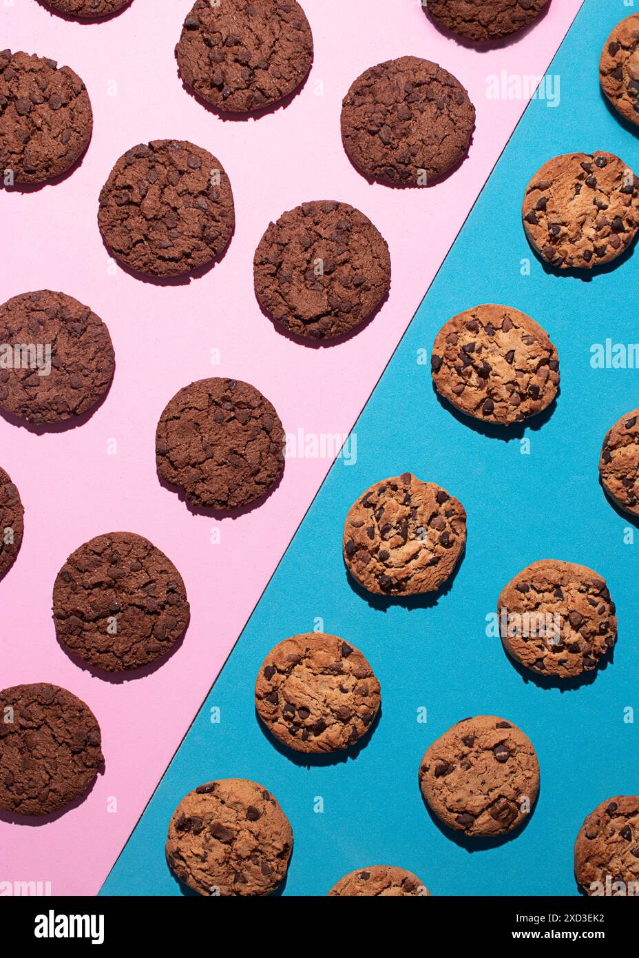 Vista dall'alto dei vari biscotti al cioccolato e dei biscotti al cioccolato doppi posizionati simmetricamente su una superficie rosa e blu a contrasto. L'immagine evidenzia Foto Stock