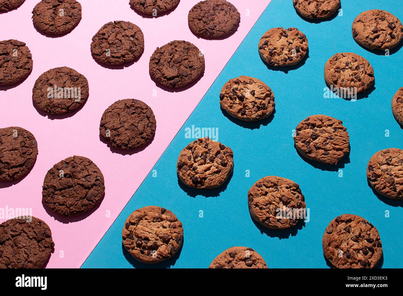 Vista dall'alto dei vari biscotti al cioccolato e dei biscotti al cioccolato doppi posizionati simmetricamente su una superficie rosa e blu a contrasto. L'immagine evidenzia Foto Stock