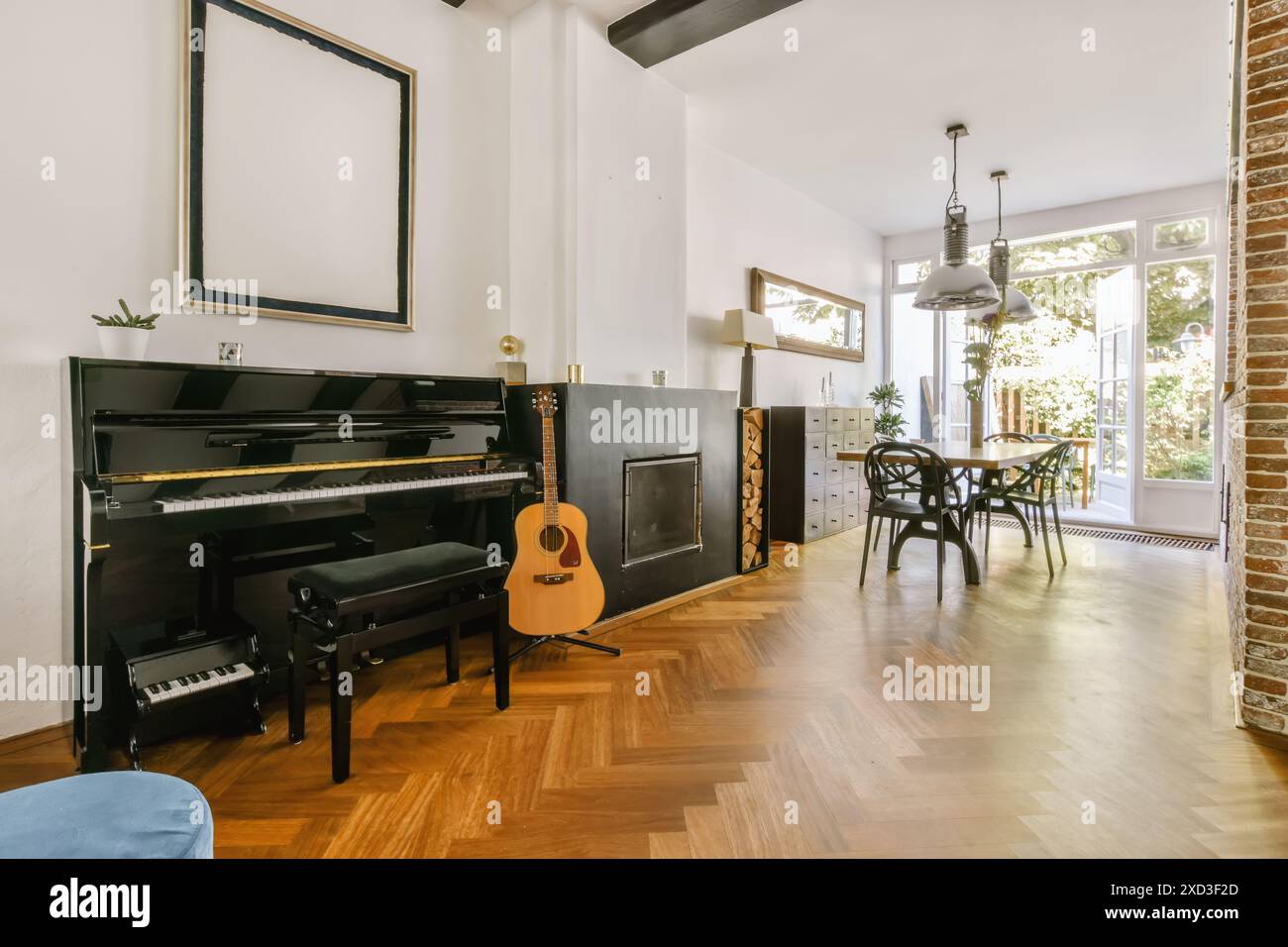 Soggiorno dal design elegante con un pianoforte a coda, una chitarra acustica e un'elegante zona pranzo con sedie alla moda e decorazioni industriali Foto Stock