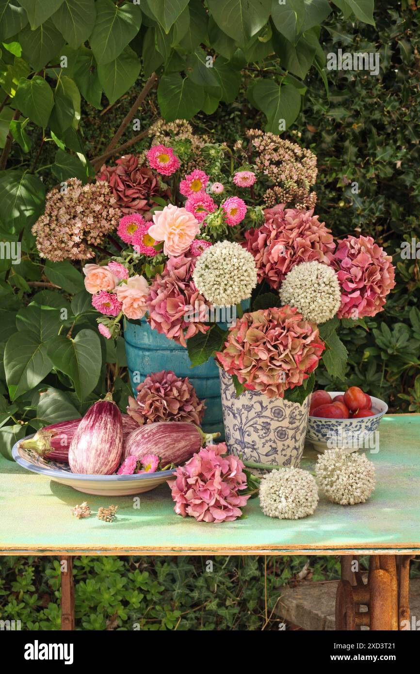 Botanica, ortensie, allium, rose e callistefo in vasi di ceramica su un tavolo di legno verde all'aperto, ULTERIORI DIRITTI-CLEARANCE-INFO-NON-DISPONIBILI Foto Stock