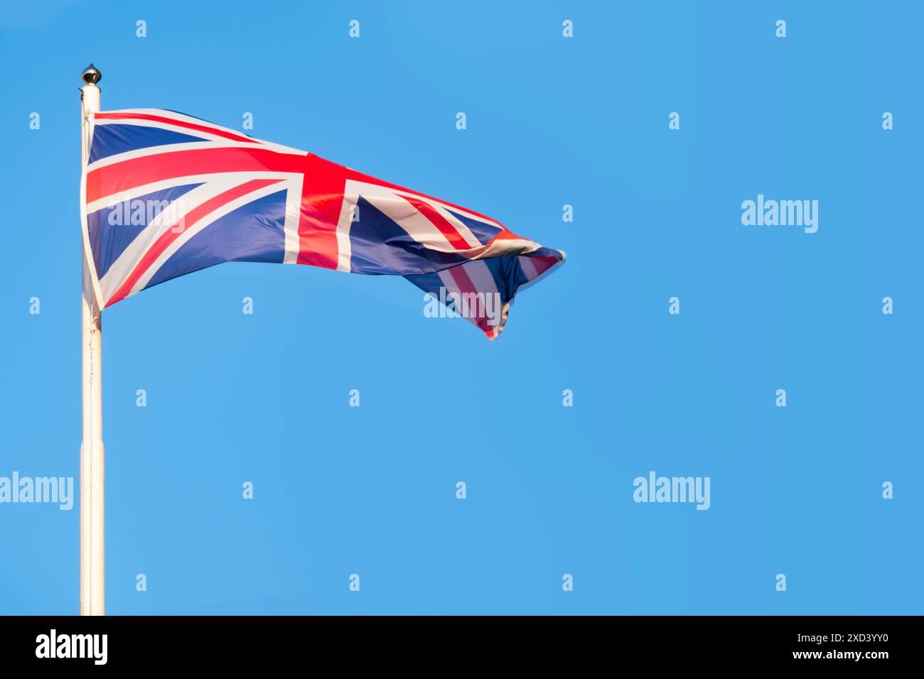 Bandiera del Regno Unito immersa nella storia, ondate contro il cielo azzurro, lo spirito duraturo e la ricca eredità del Regno Unito, Union Jack Foto Stock