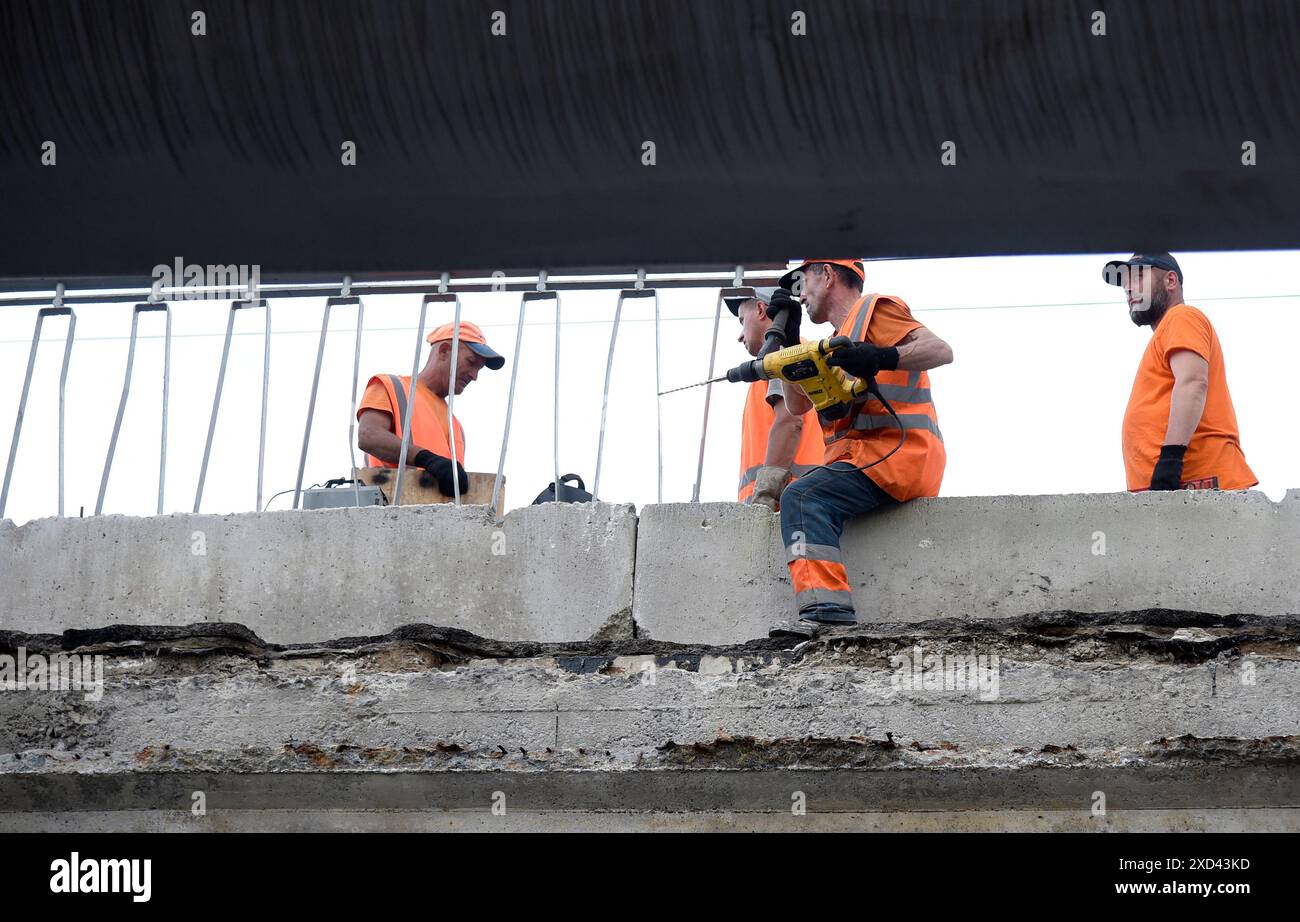 KIEV, UCRAINA - 20 GIUGNO 2024 - i lavoratori riparano i frammenti della sezione pedonale del cavalcavia Povitroflotskyi che è crollato su binari del tram mercoledì 19 giugno, Kiev, capitale dell'Ucraina. Foto Stock