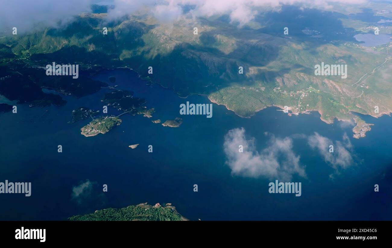 Vista aerea attraverso le nuvole fino alla baia marina con le colline costiere. Vista dall'alto dalle nuvole ai fiordi norvegesi Foto Stock