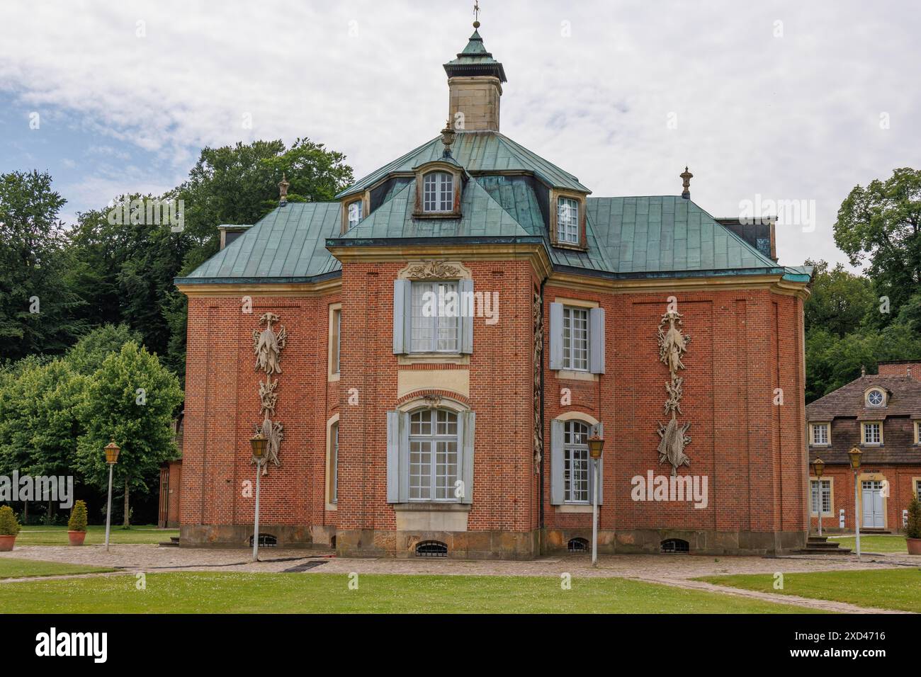 Edificio storico con facciata in mattoni e tetti verdi in metallo, circondato da un'area giardino, Soegel, emsland, Germania Foto Stock