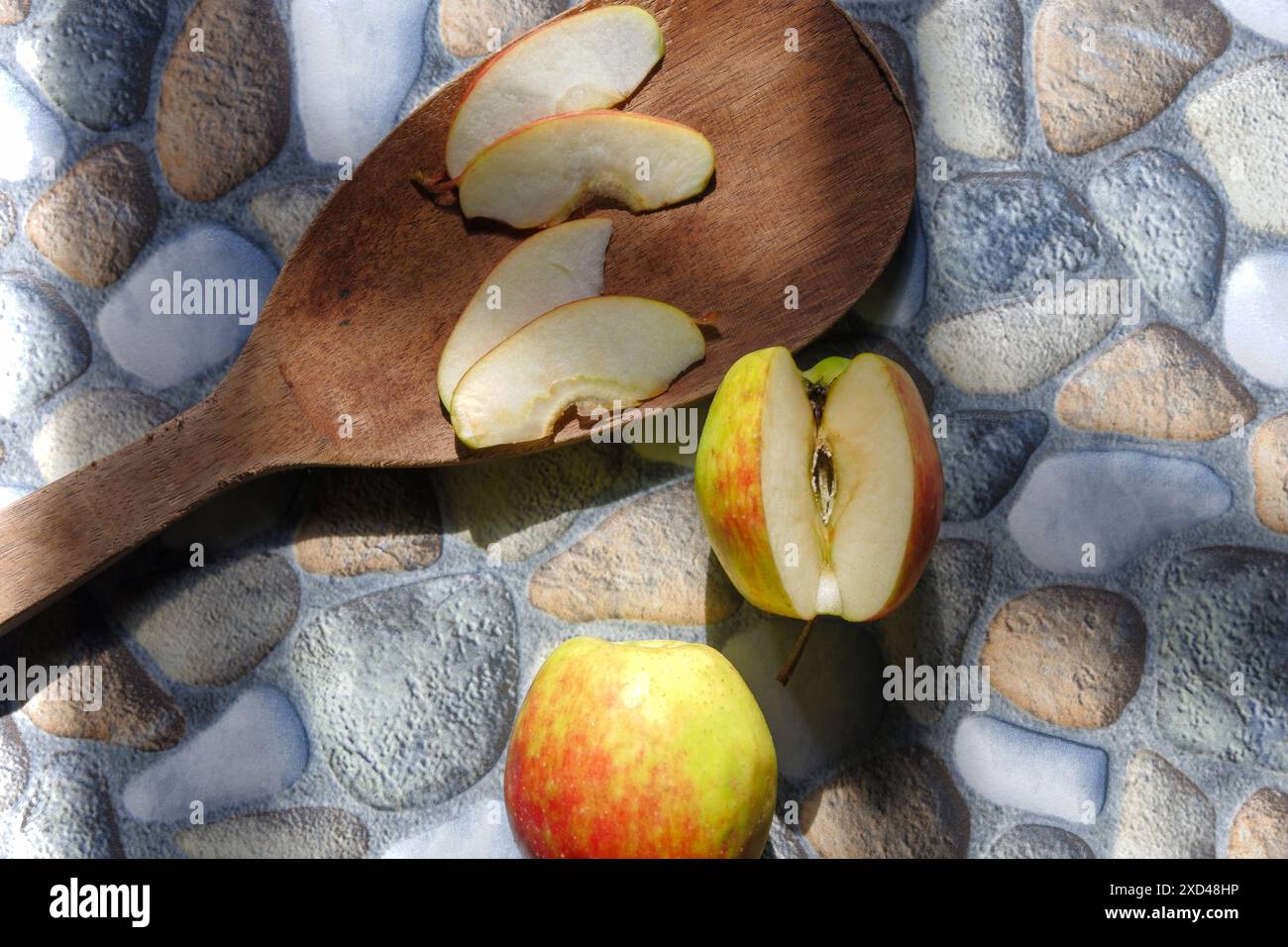 foto di mele in vari stili, alcune ancora intatte, altre tagliate con uno sfondo di pietra Foto Stock