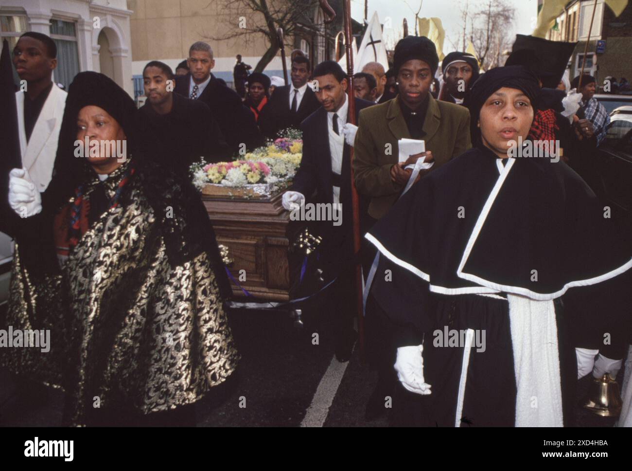 La chiesa battista spirituale del monte Zion, il vescovo George Gifford Noel di Grenada era morto, i membri della comunità ecclesiastica seguono la processione mentre la bara viene fatta rotolare attraverso la strada fino al Kensal Green Cemetery. Madre Twila Noel (a sinistra) conduce la processione funebre. Kensal Green, Londra, Inghilterra 1994 1990s UK HOMER SYKES Foto Stock