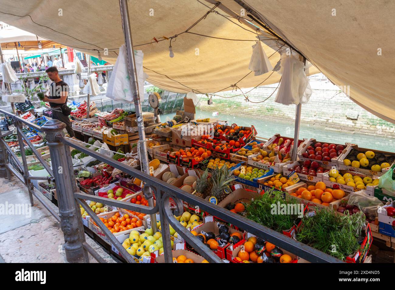 Venditore che vende prodotti freschi su un battello del mercato in un canale vicino via Garibaldi, Castello, Venezia Foto Stock
