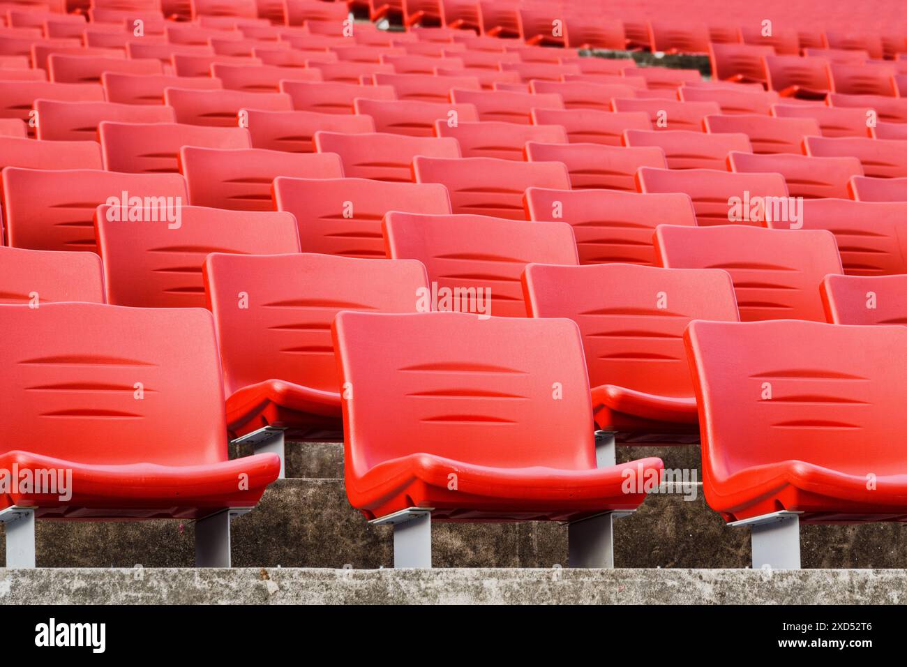 File di posti vuoti in uno stadio. Sedili a teatro in plastica rossa. Foto Stock