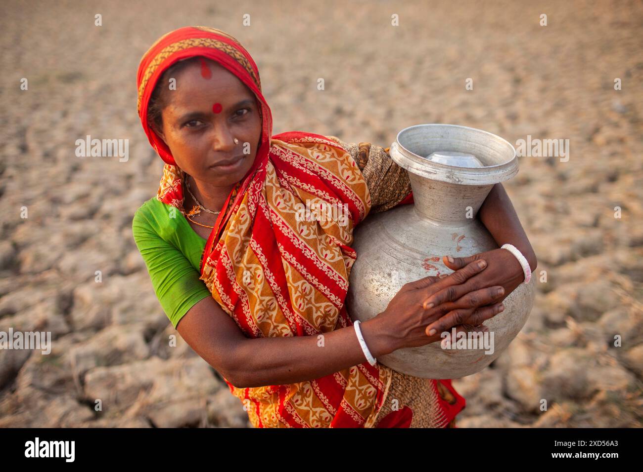 20 giugno 2024, Dacca, Dacca, Bangladesh: Una donna del Bangladesh che trasporta acqua potabile dopo averla raccolta da una fonte di acqua dolce, camminando molto per raccogliere acqua potabile nella zona costiera di Khulna, Bangladesh. Secondo una ricerca dell'American Geophysical Union, l'innalzamento del livello del mare, che sta influenzando la disponibilità di acqua potabile pulita, causerà la migrazione di circa 1,3 milioni di persone in tutto il paese entro il 2050. Una combinazione di inondazione delle maree, inondazione delle tempeste e intrusione di acqua salata sta portando a un aumento della salinità nelle acque sotterranee e nello stagno di acqua dolce Foto Stock