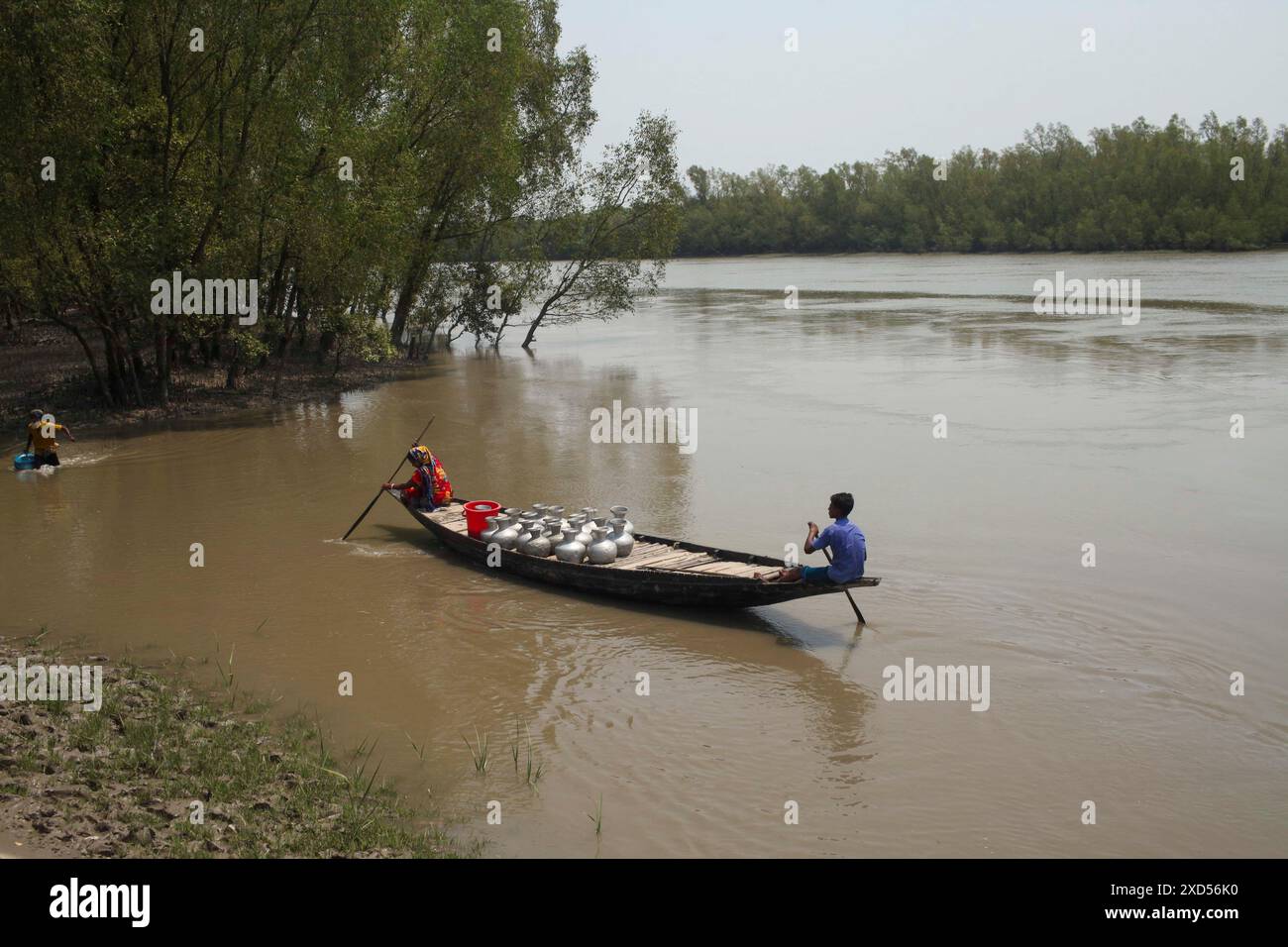 20 giugno 2024, Dacca, Dacca, BANGLADESH: Una donna viene vista con suo figlio su una barca per raccogliere acqua potabile da una fonte di acqua dolce nella zona costiera di Khulna. Una combinazione di inondazioni di marea, inondazioni da picchi di tempesta e intrusioni di acqua salata ha portato a un aumento della salinità nelle acque sotterranee e negli stagni di acqua dolce, causando una crisi acuta di acqua potabile nella zona costiera del Bangladesh, soprattutto in diverse aree di Khulna. Le fonti di acqua potabile sono spesso contaminate o situate così lontano che sono necessarie ore di viaggio (a piedi) per garantire il fabbisogno idrico quotidiano, in aree spesso r Foto Stock