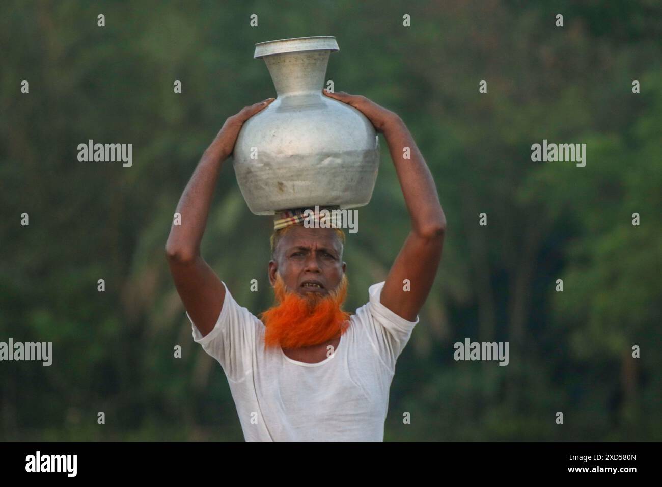 20 giugno 2024, Dacca, Dacca, BANGLADESH: Un uomo bengalese che trasporta acqua potabile dopo averla raccolta da una fonte di acqua dolce, camminando molto per raccogliere acqua potabile nella zona costiera di Khulna, Bangladesh. Secondo una ricerca dell'American Geophysical Union, l'innalzamento del livello del mare, che sta influenzando la disponibilità di acqua potabile pulita, causerà la migrazione di circa 1,3 milioni di persone in tutto il paese entro il 2050. Una combinazione di inondazioni mareali, inondazioni di tempeste e intrusioni di acqua salata sta portando a un aumento della salinità nelle acque sotterranee e negli stagni di acqua dolce, Foto Stock