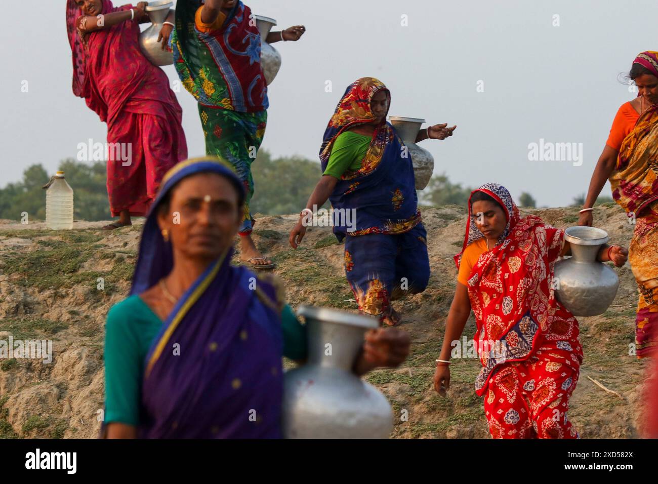 20 giugno 2024, Dacca, Dacca, BANGLADESH: Le donne del Bangladesh trasportano acqua potabile dopo averla raccolta da una fonte di acqua dolce, camminando molto per raccogliere acqua potabile nella zona costiera di Khulna, Bangladesh. Secondo una ricerca dell'American Geophysical Union, l'innalzamento del livello del mare, che sta influenzando la disponibilità di acqua potabile pulita, causerà la migrazione di circa 1,3 milioni di persone in tutto il paese entro il 2050. Una combinazione di inondazione delle maree, inondazione delle tempeste e intrusione di acqua salata sta portando a un aumento della salinità nelle acque sotterranee e nelle acque dolci del po Foto Stock