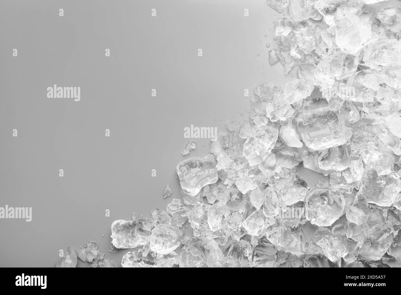 Pezzi di ghiaccio tritato su sfondo grigio, vista dall'alto. Spazio per il testo Foto Stock