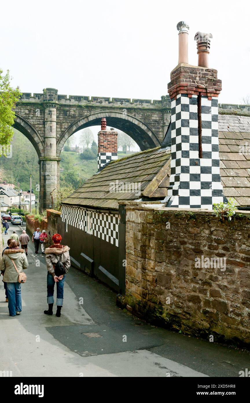 I turisti passano davanti a un edificio con motivi a scacchiera a Knaresborough, nello Yorkshire, vicino al viadotto di Nidd Valley Foto Stock