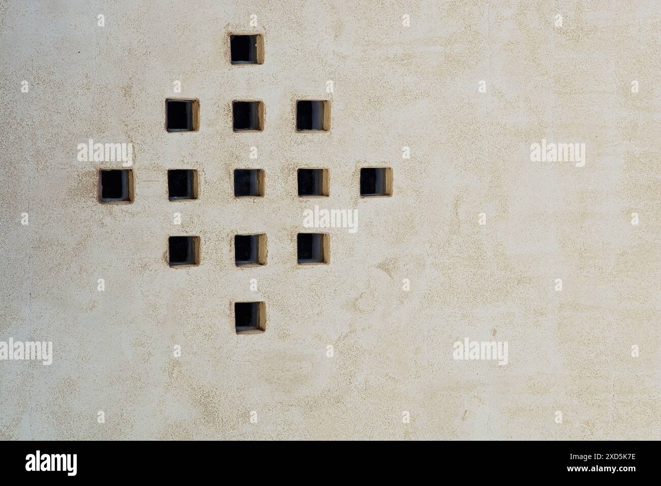 Piccoli mattoni quadrati di vetro distanziati in forma quadrata attraverso pareti rivestite in stucco Foto Stock