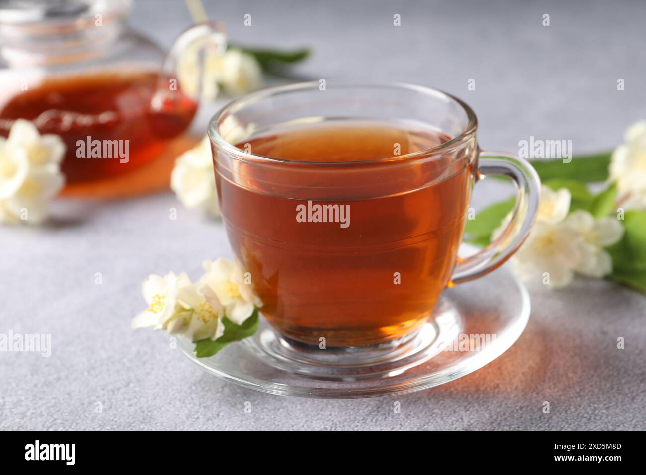 Tè caldo al gelsomino in tazza e fiori su un tavolo grigio chiaro Foto Stock