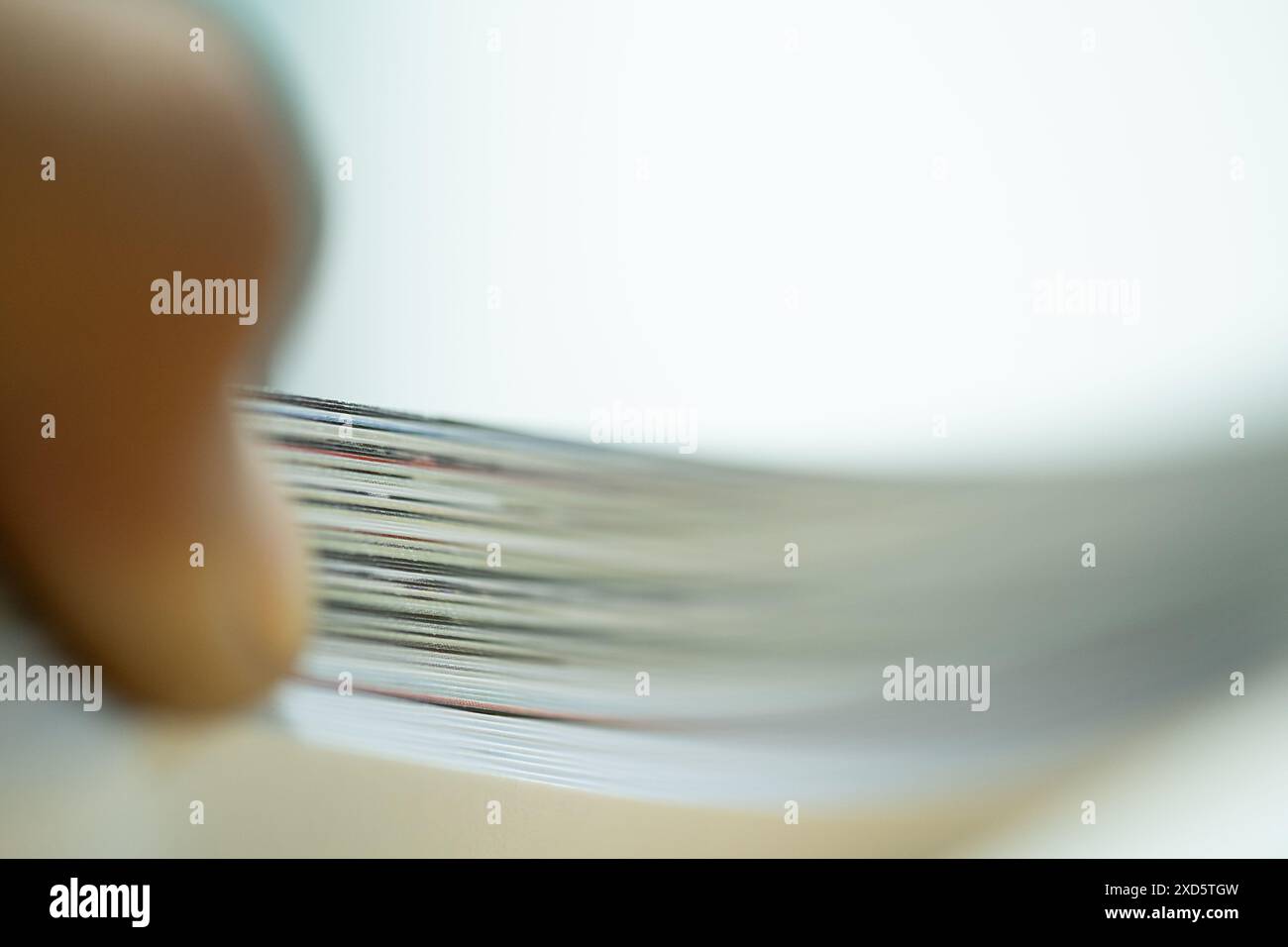 Primo piano di una persona che sfoglia una pila di documenti, creando un effetto di movimento sfocato. Foto Stock