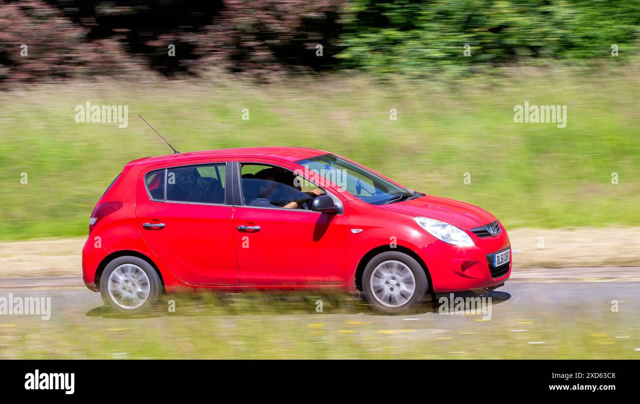Milton Keynes, Regno Unito - 20 giugno 2024: 2012 auto Hyundai i20 rossa che guida su una strada di campagna britannica Foto Stock