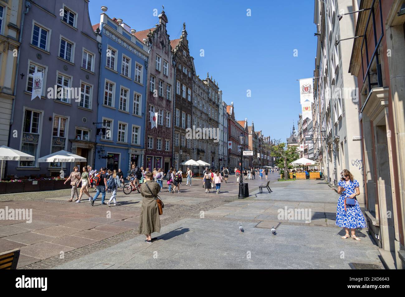 I turisti si godono una giornata di sole in via Długa a Danzica, fiancheggiata da colorati edifici storici e caffetterie all'aperto. Foto Stock