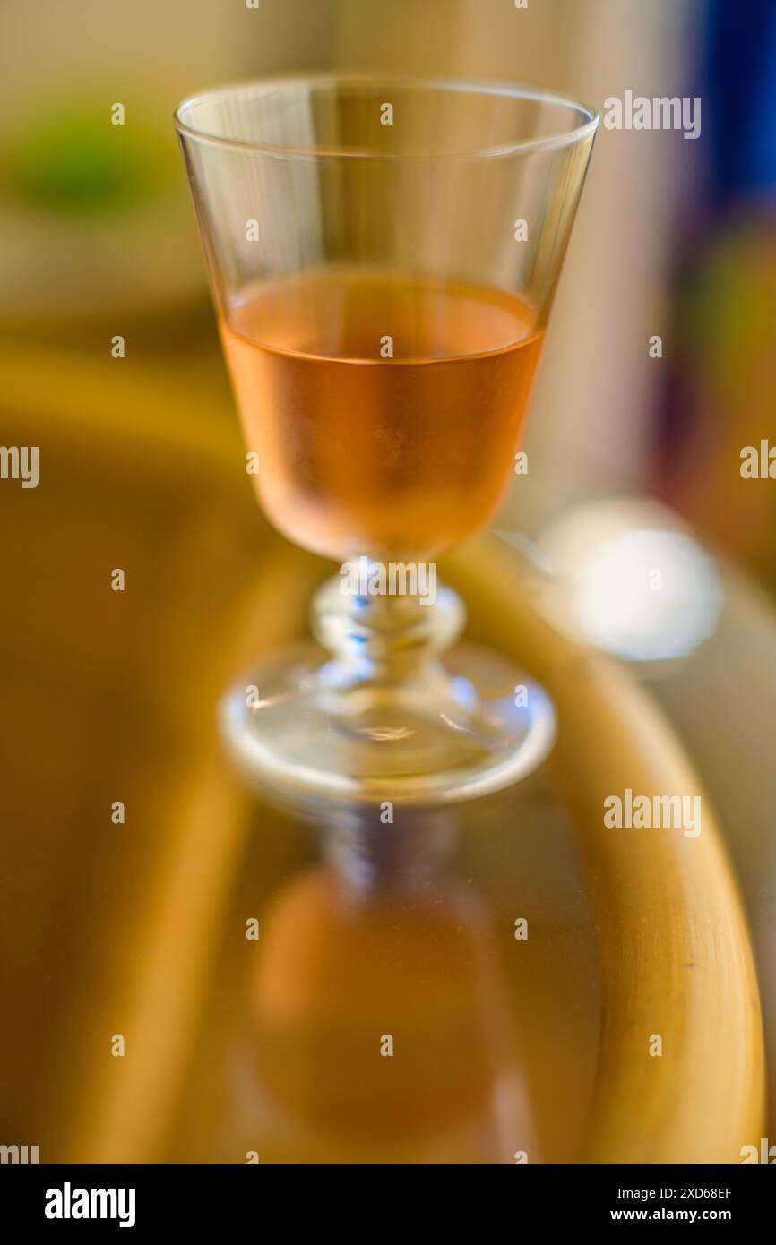 Una foto mirata di un bicchiere di vino rosato seduto su un tavolo, evidenziandone il colore e la forma eleganti. Foto Stock