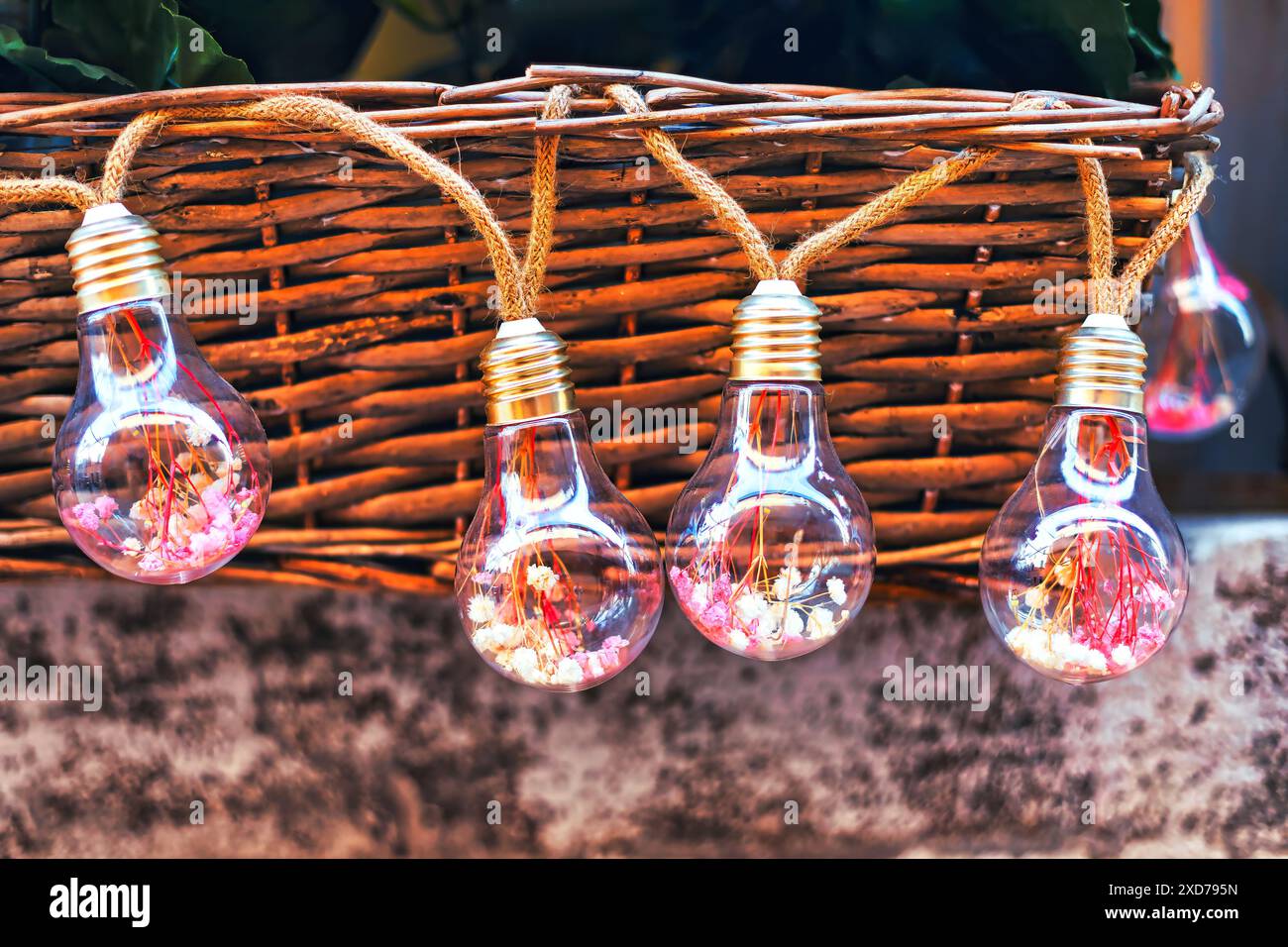 Lampadine in un cestello di vimini sullo sfondo della parete. Atmosfera affascinante e illuminata Foto Stock