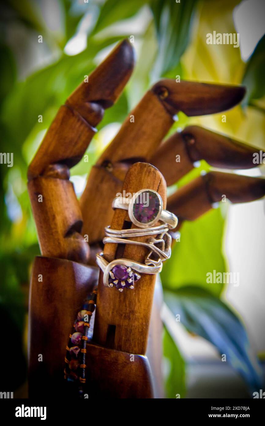 Anelli e altri gioielli disposti su una mano di legno Foto Stock