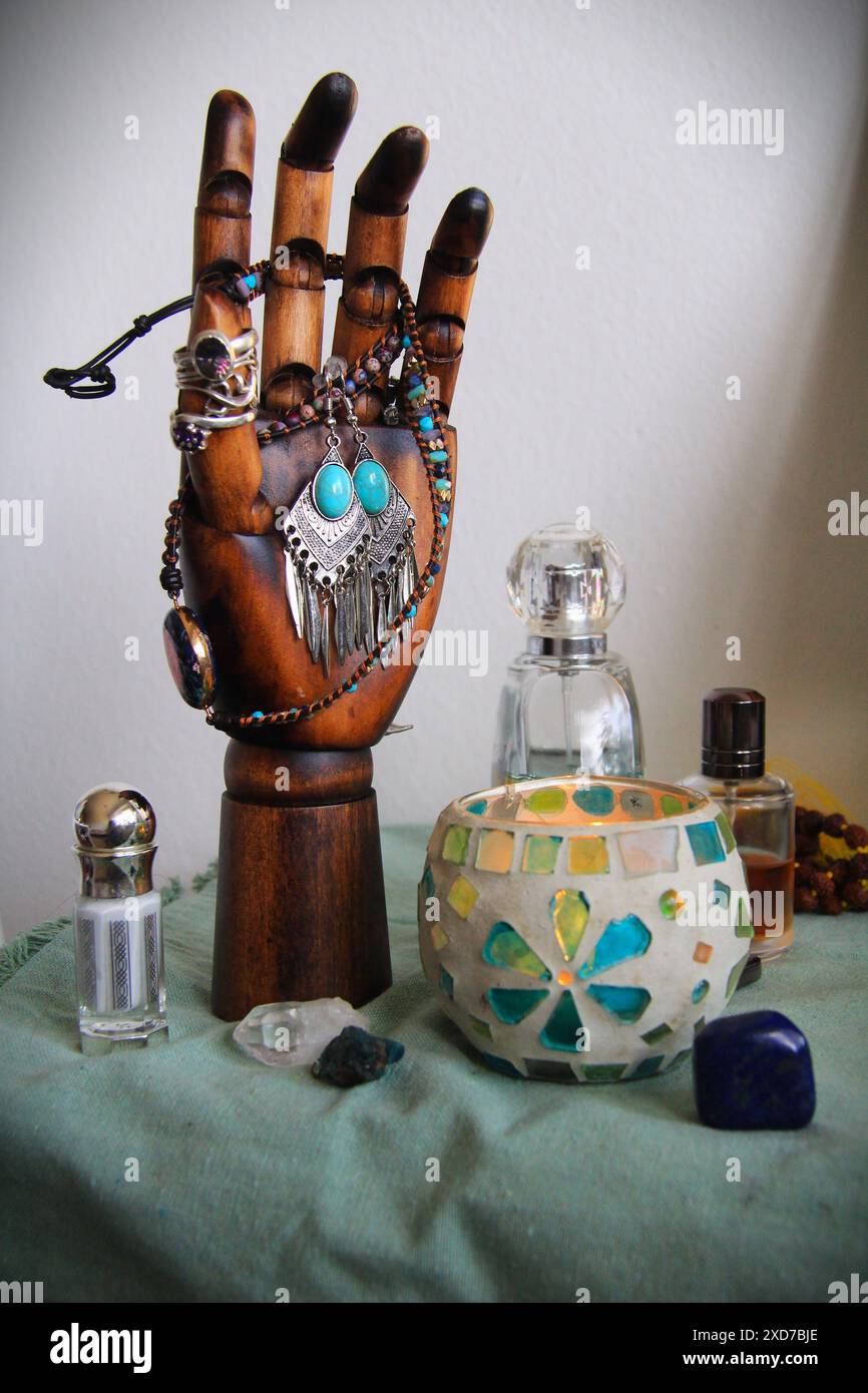 Anelli e altri gioielli disposti su una mano di legno Foto Stock