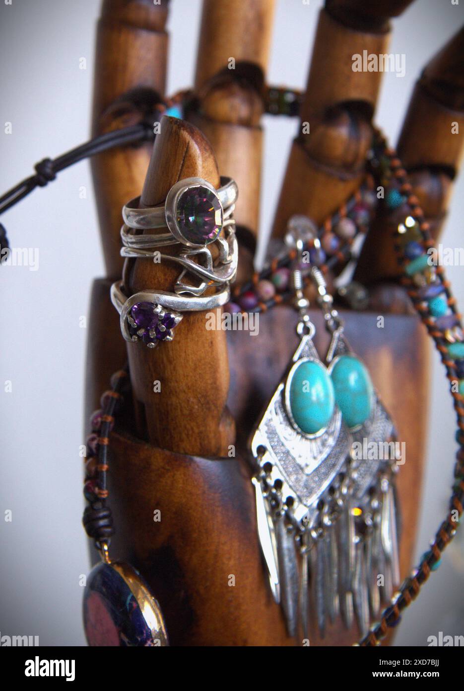 Anelli e altri gioielli disposti su una mano di legno Foto Stock