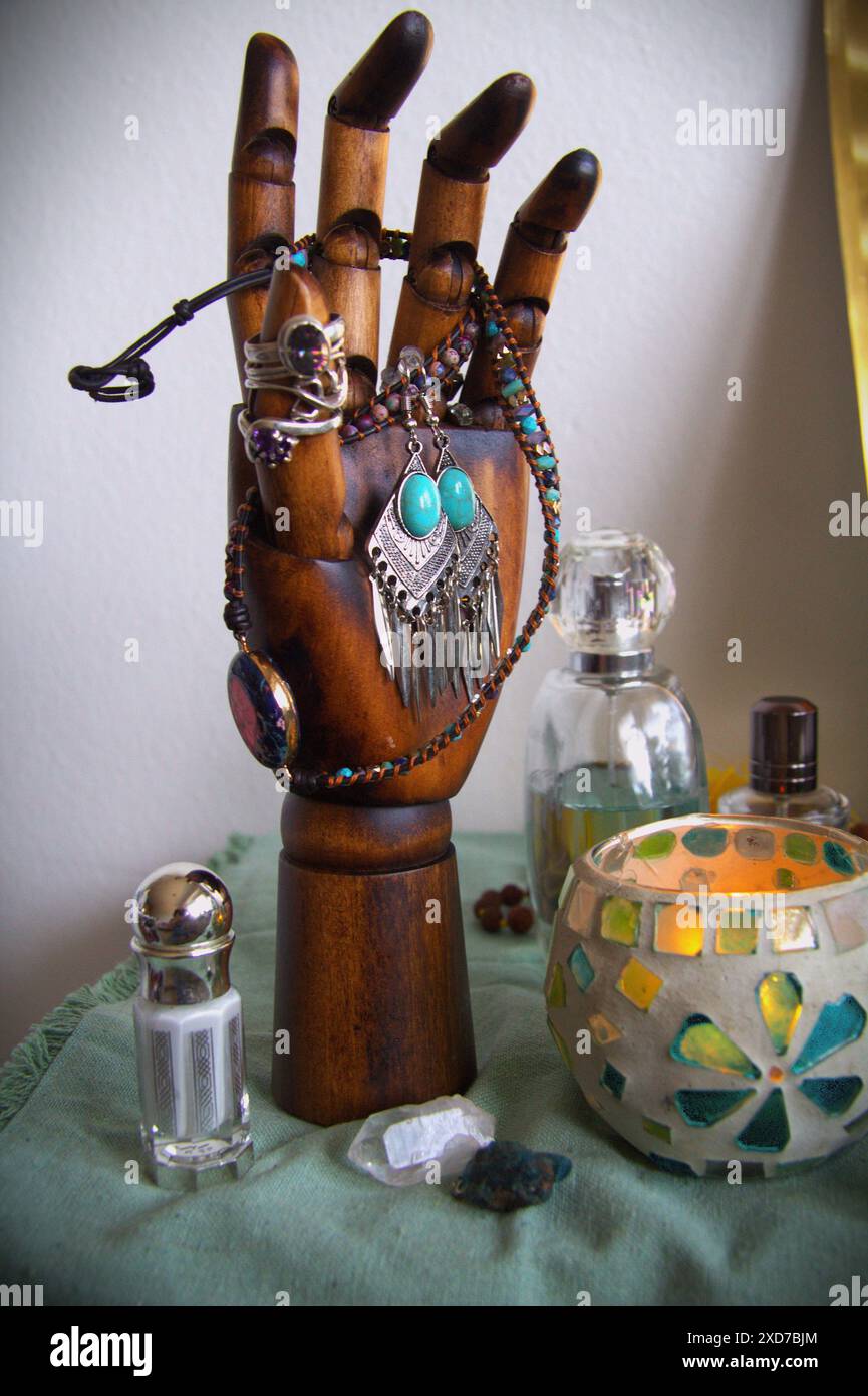Anelli e altri gioielli disposti su una mano di legno Foto Stock