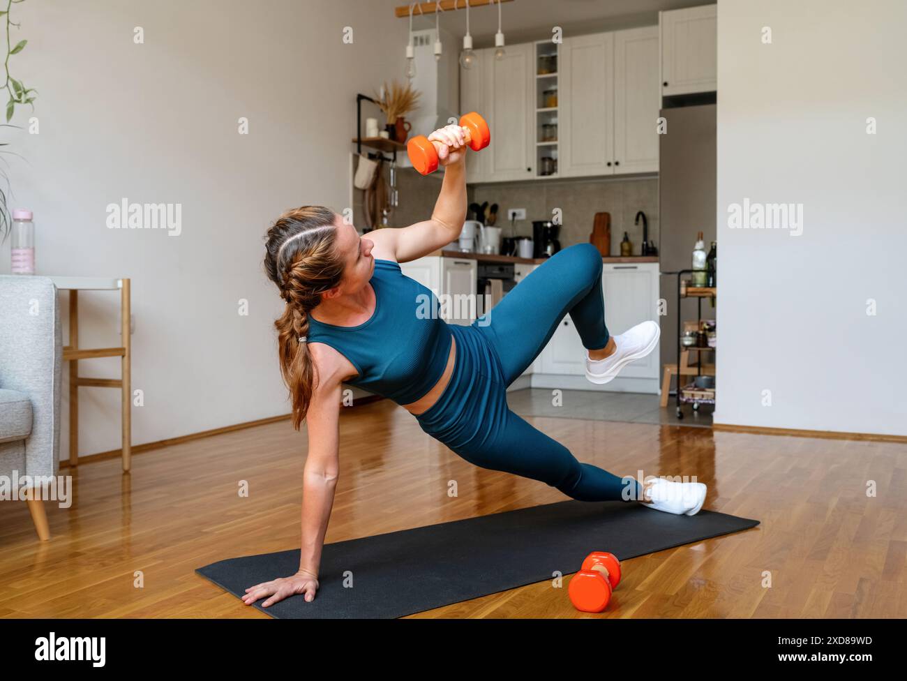 Donna atletica che fa un duro allenamento a casa. Donna che fa esercizio con il manubrio. Foto Stock
