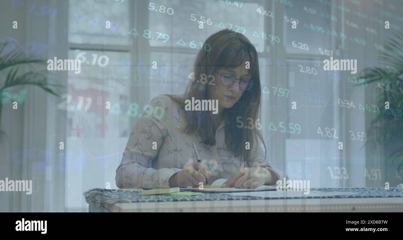Immagine dell'elaborazione dei dati del mercato azionario contro una donna caucasica premurosa che prende appunti in ufficio Foto Stock