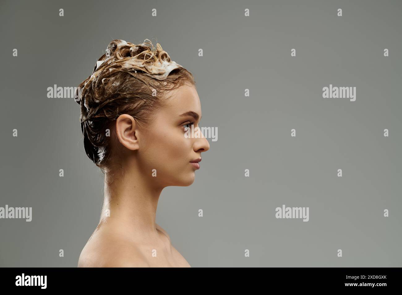 Bella donna che applica il prodotto per la cura dei capelli e lava i capelli. Foto Stock