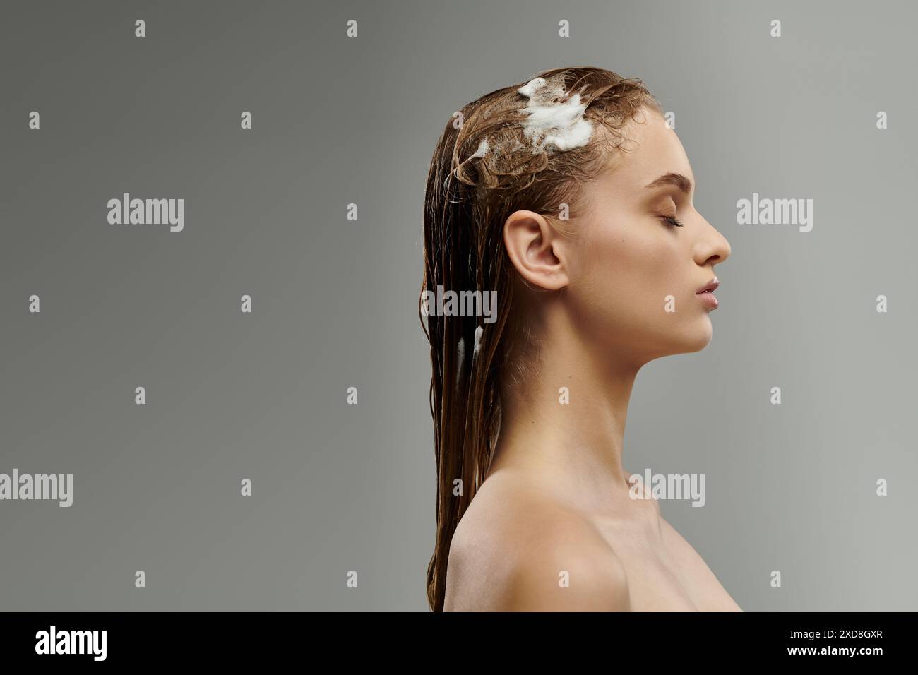 Donna attraente che applica un prodotto per la cura dei capelli e lava i capelli. Foto Stock