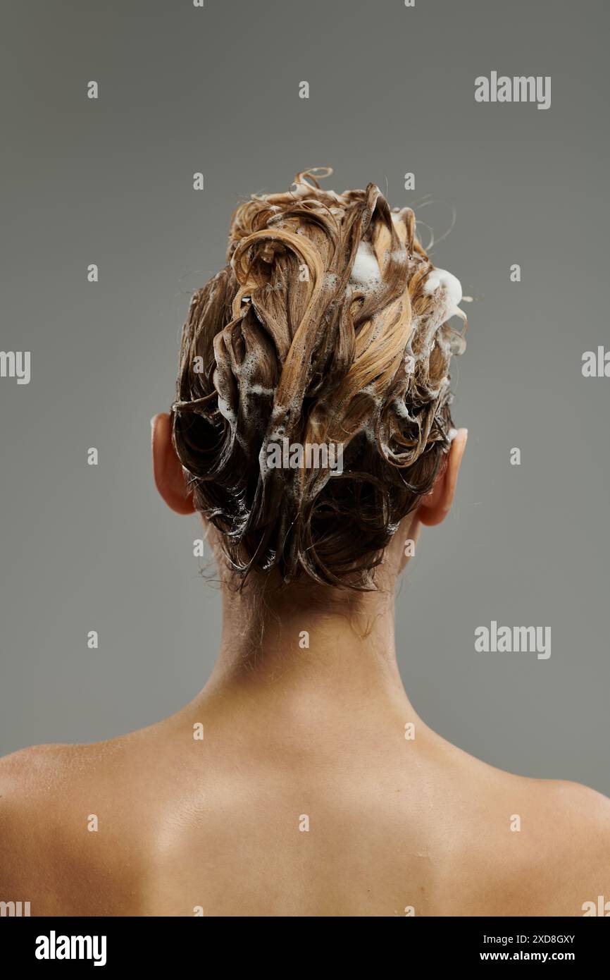 Donna chic che applica un prodotto per la cura dei capelli e lava i capelli. Foto Stock