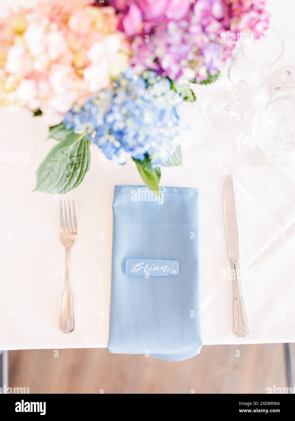Sistemare con il centrotavola floreale del tovagliolo blu e il biglietto del nome Foto Stock