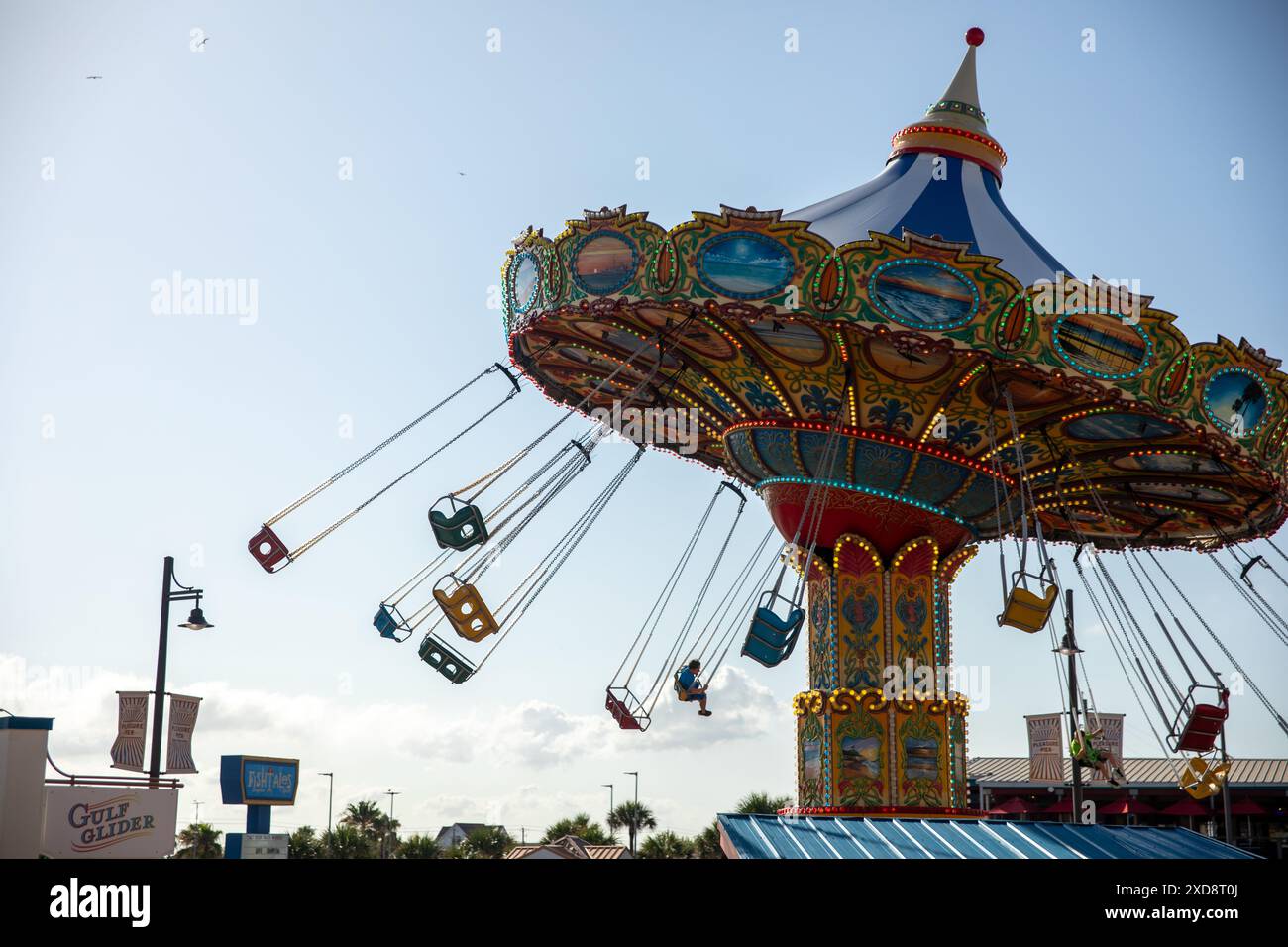 Giostra colorata a dondolo con i piloti in movimento contro un cielo blu. Foto Stock