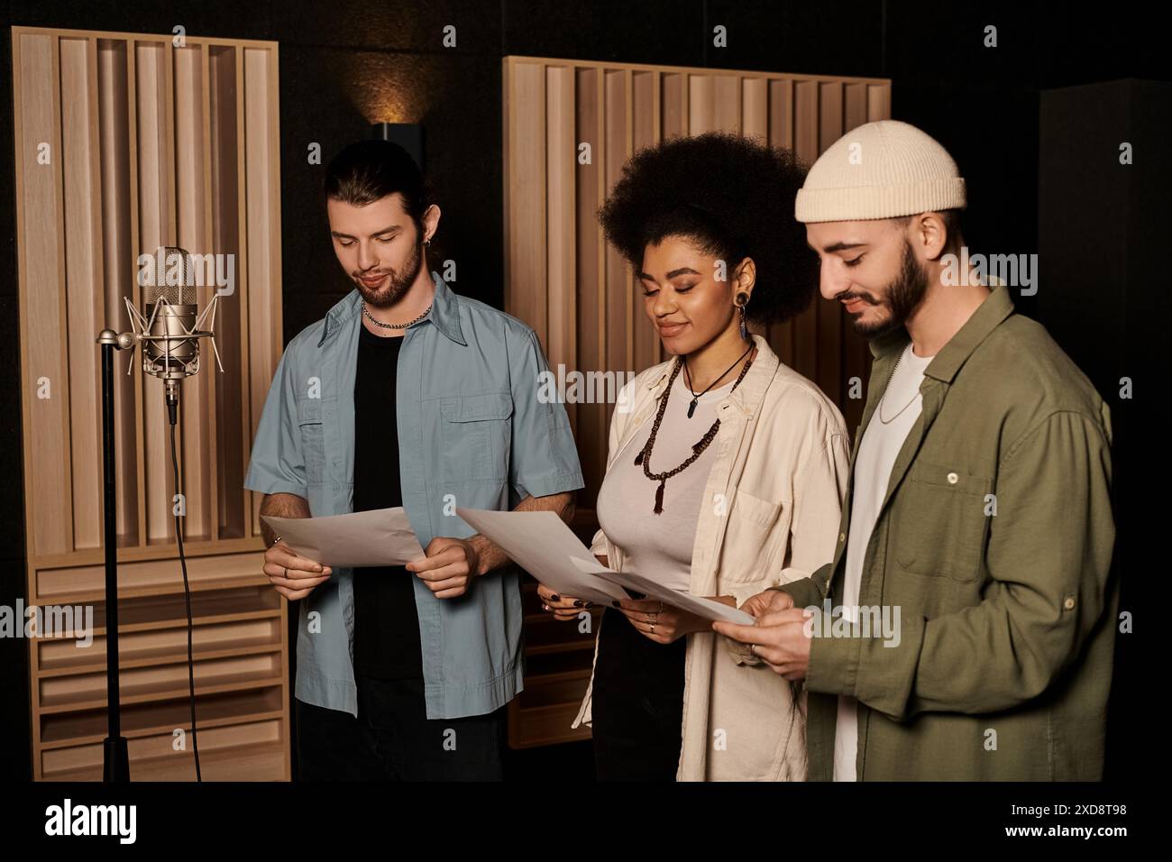 Una band di musica prova in uno studio di registrazione, in piedi insieme mentre si preparano per il loro prossimo progetto. Foto Stock