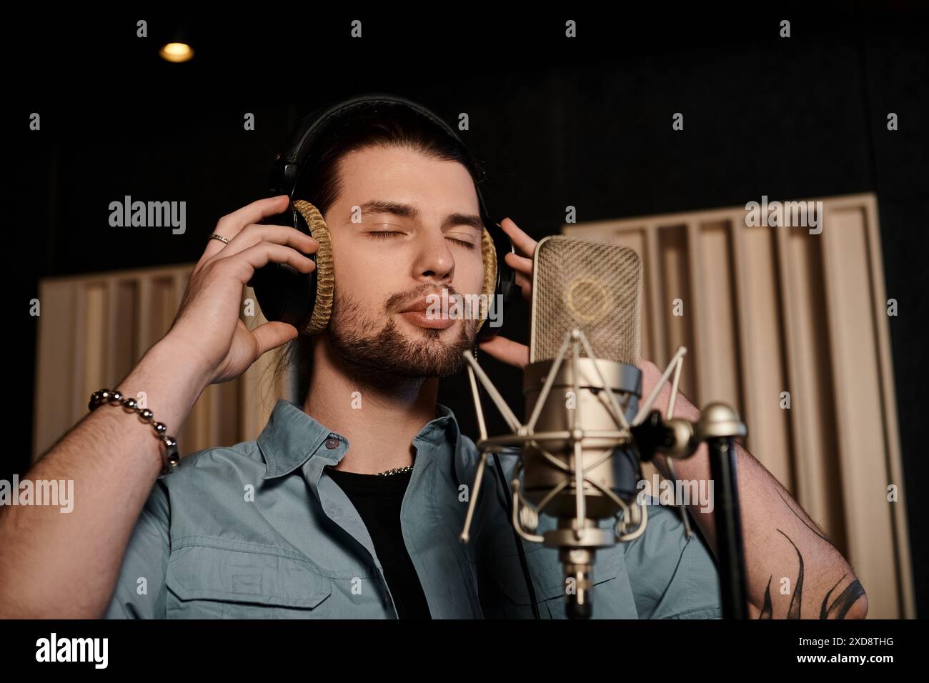 Un uomo immerso nella musica, che indossa le cuffie, che mixa brani in uno studio di registrazione durante una sessione di prova di una band musicale. Foto Stock