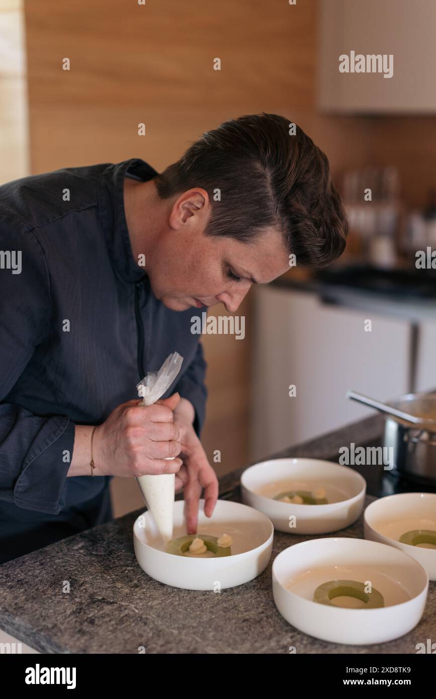 Lo chef condendo con cura la salsa in ciotole per un piatto gourmet Foto Stock