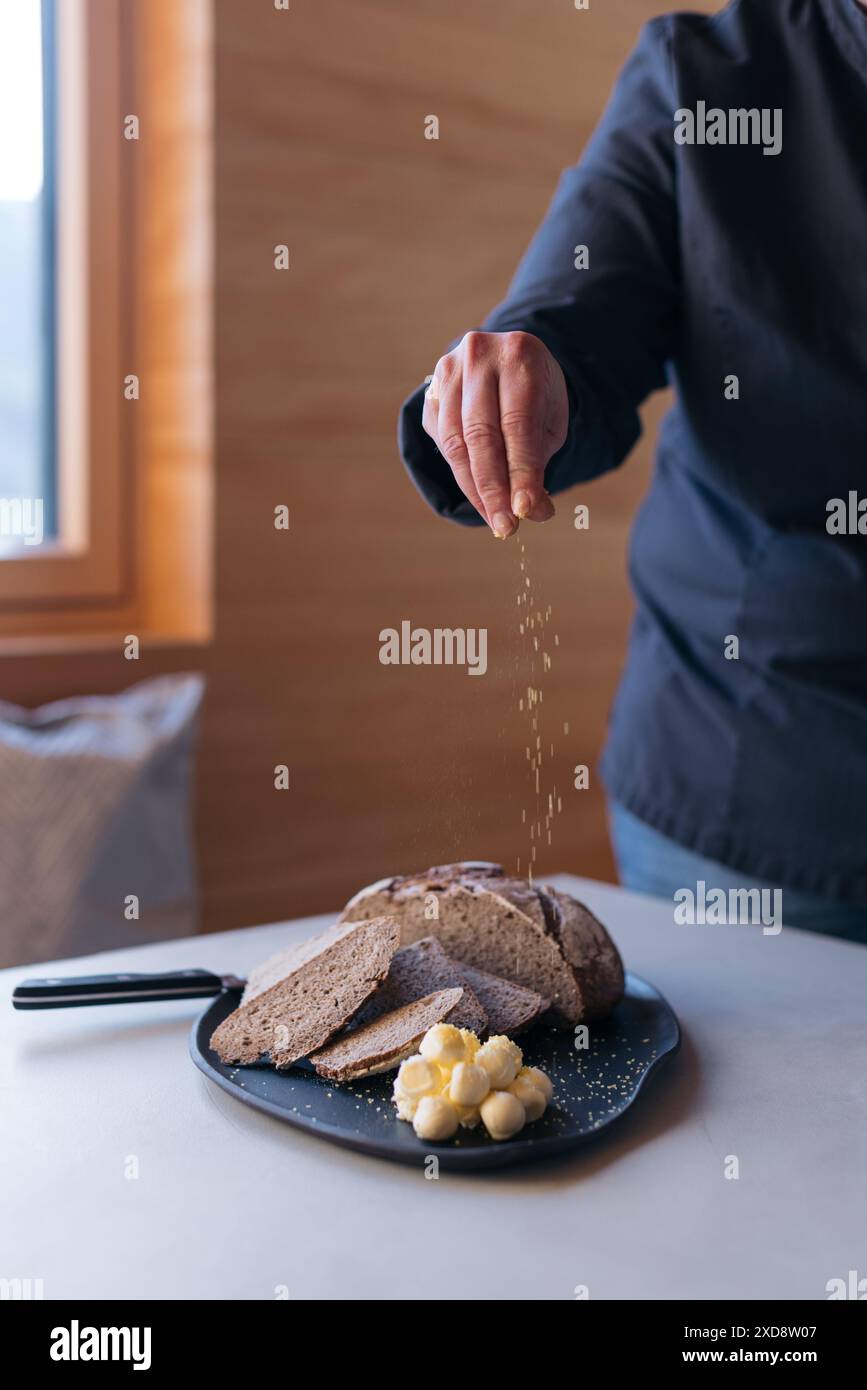 Lo chef spolvererà sale sul pane fresco con ricci al burro Foto Stock