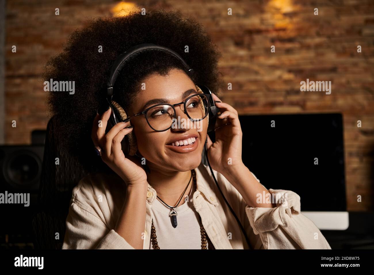 Una giovane donna che indossa le cuffie in uno studio di registrazione, immersa nella produzione musicale per una sessione di prove della band. Foto Stock