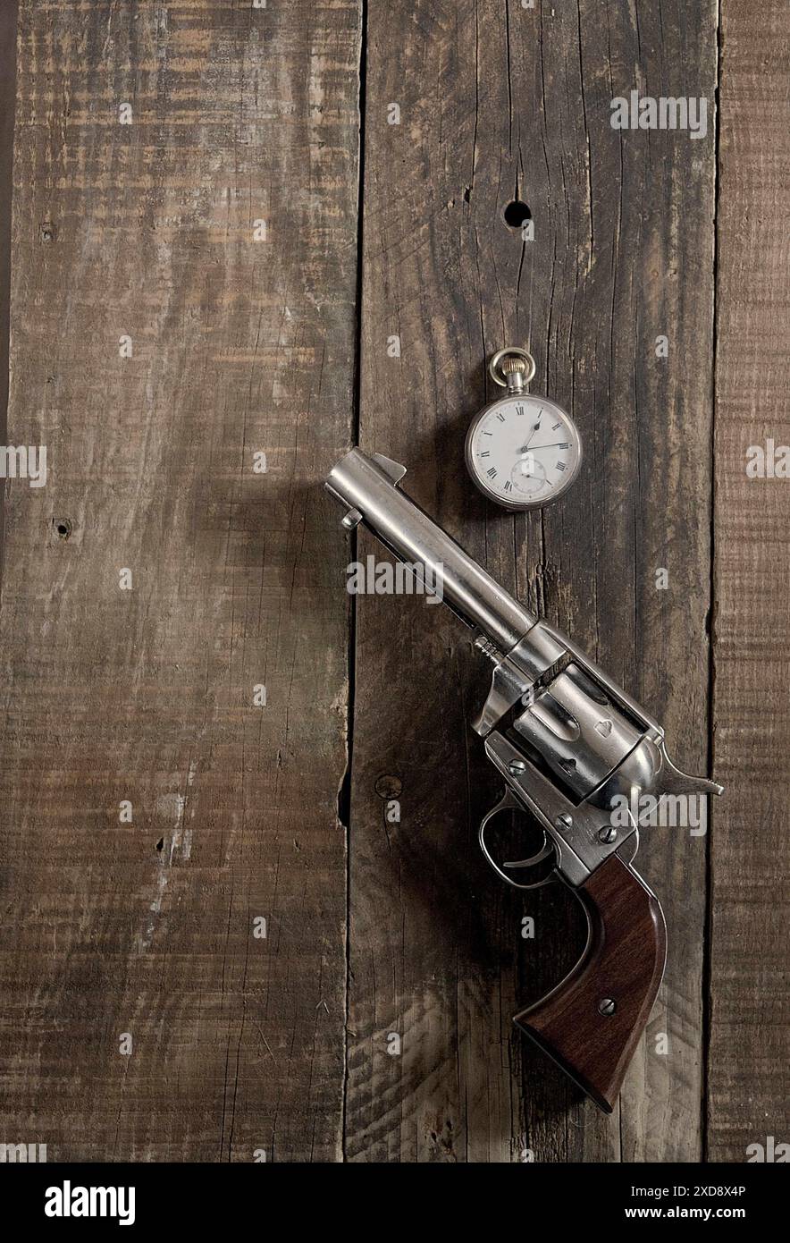 Selvaggio West, a mezzogiorno. Cowboy 6 cannoni e orologio da tasca argento steso su un vecchio tavolo di legno. Cowboy, western, tema. Foto Stock