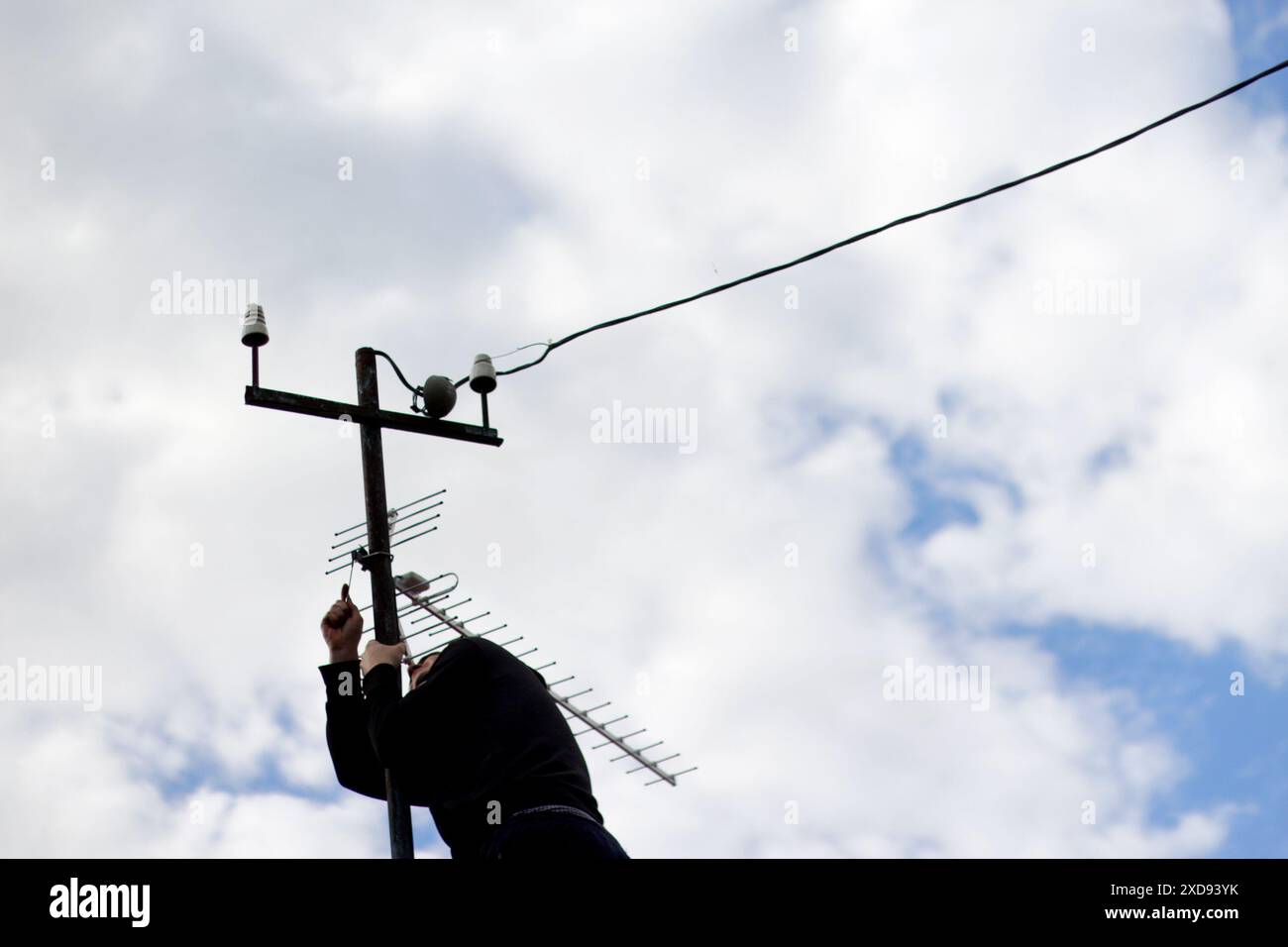 Cavo di collegamento manuale all'antenna 4G da vicino con il cielo sullo sfondo. Tecnico che ripara l'antenna, uomo che ripara il segnale TV. Intervento di manutenzione sul tetto Foto Stock