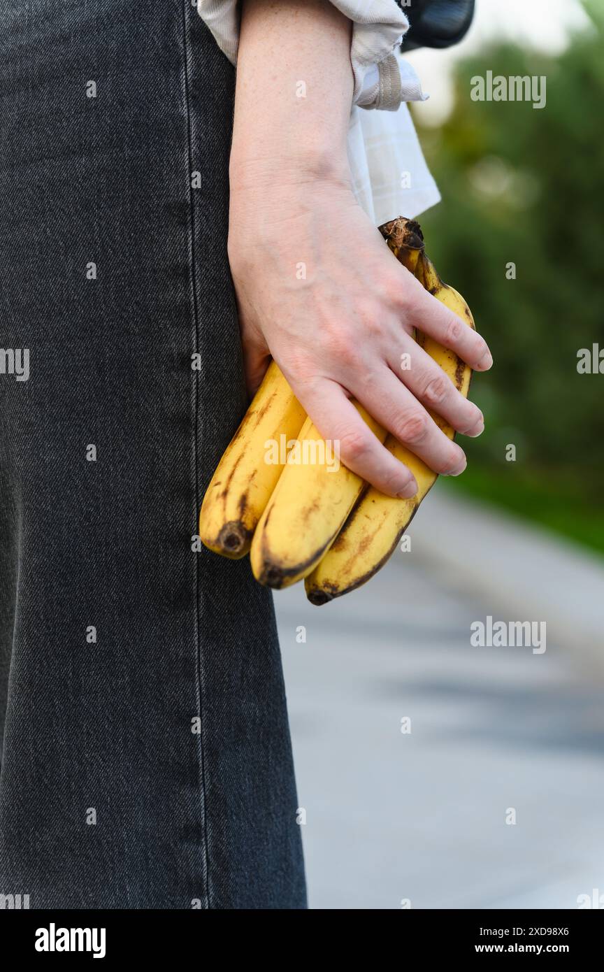 Primo piano della mano di una donna che tiene le banane mature. Concetto di spuntino veloce. Foto Stock