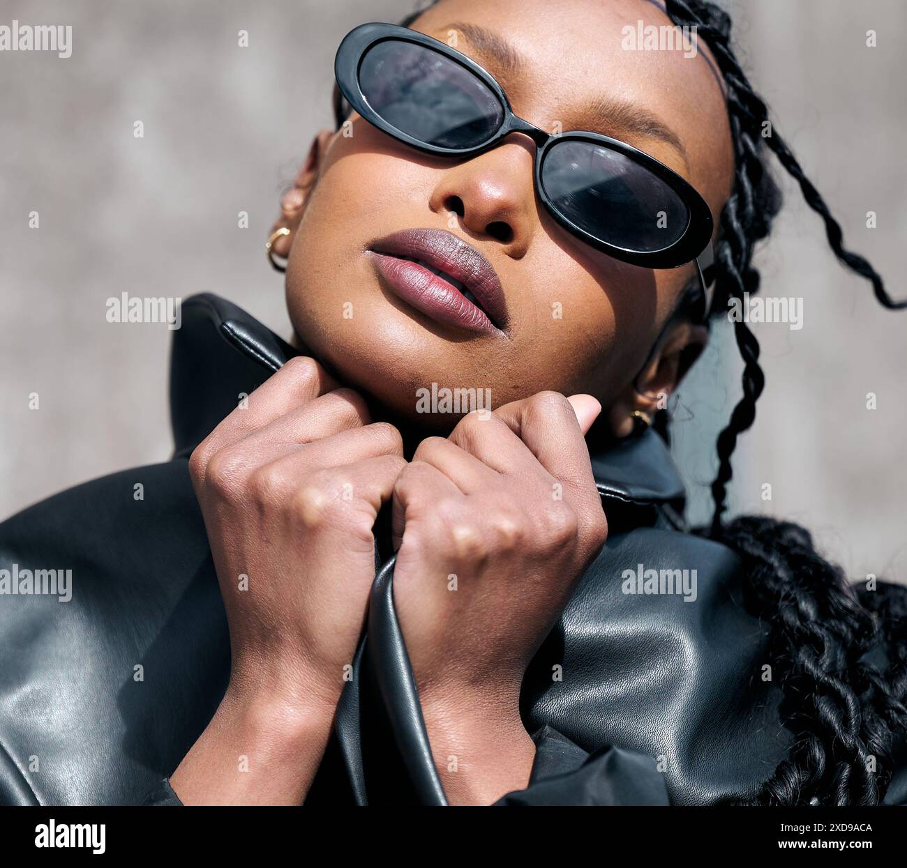 la bella modella nera tiene il collare della giacca con entrambe le mani sul viso Foto Stock