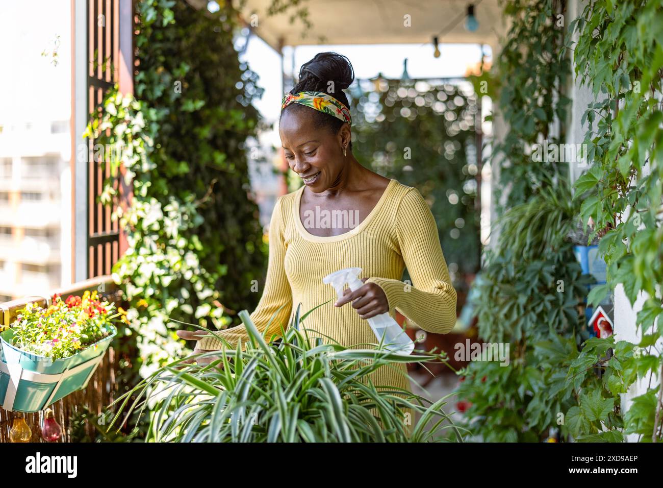 Bella donna che innaffiava le piante sul balcone Foto Stock