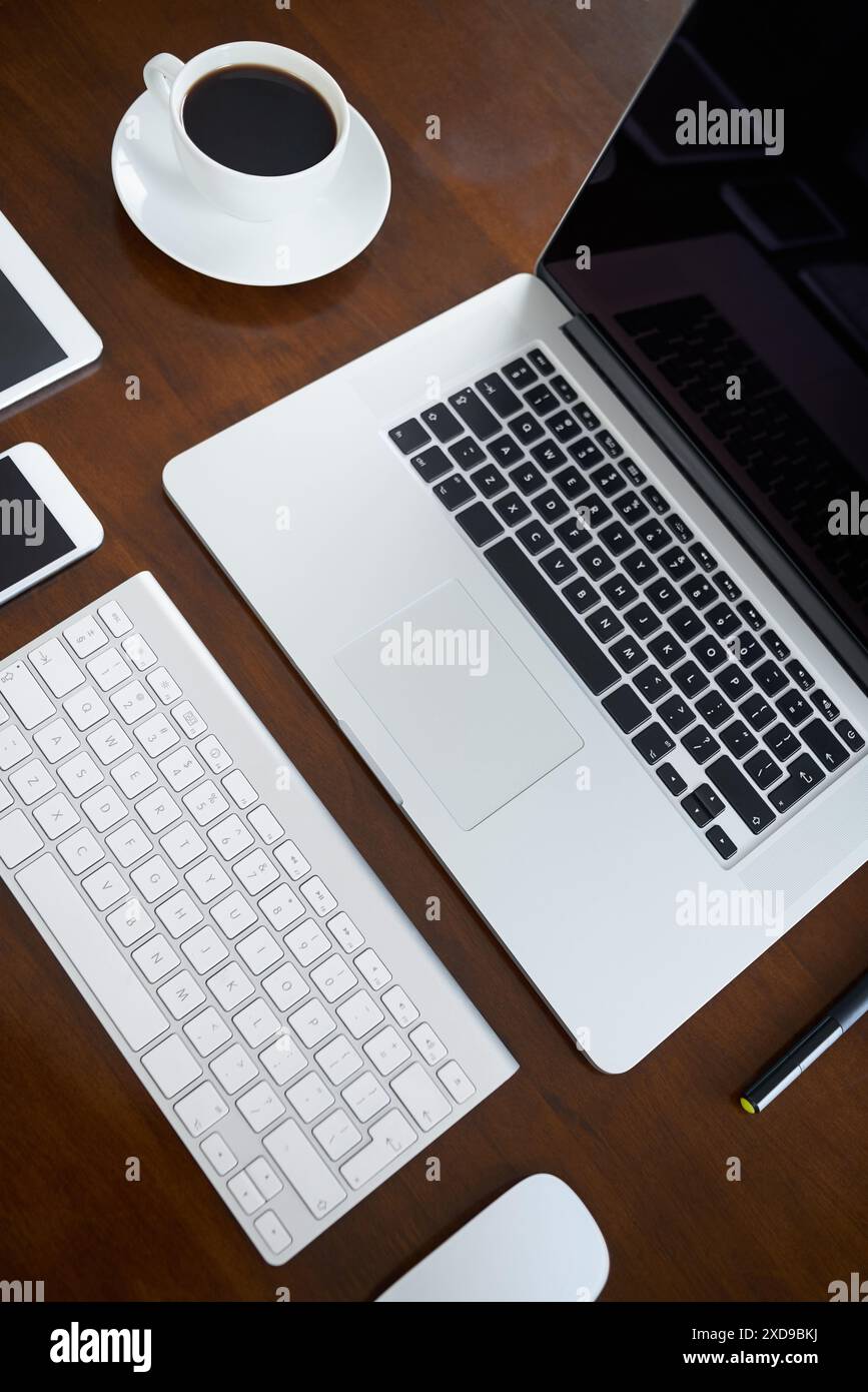 Notebook, dispositivi mobili e tablet in ufficio con dispositivi digitali per la ricerca aziendale, la comunicazione o la collaborazione. Smartphone, mouse e caffè Foto Stock