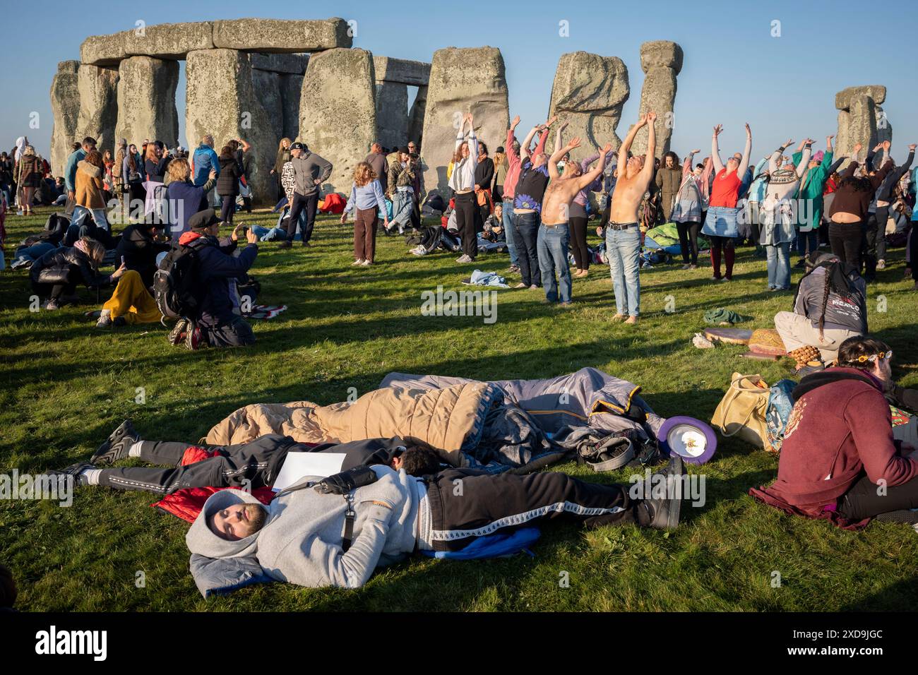 Una classe di yoga di rivelatori spiritualmente mentali celebrano il solstizio d'estate (metà estate e giorno più lungo) presso le antiche pietre tardo-neolitiche di Stonehenge, il 21 giugno 2024, nel Wiltshire, Inghilterra. Il solstizio d'estate è il giorno più lungo dell'emisfero settentrionale e la notte più breve dell'anno, quando l'asse terrestre è inclinato nel punto più vicino al sole e i pagani dicono che l'antico monumento è un luogo sacro che collega la Terra, la Luna, il Sole e le stagioni. Stonehenge è stata costruita in tre fasi tra il 3.000 a.C. e il 1.600 a.C. Stonehenge è di proprietà dell'English Heritage, che dice lo fossero 15.000 visitatori Foto Stock