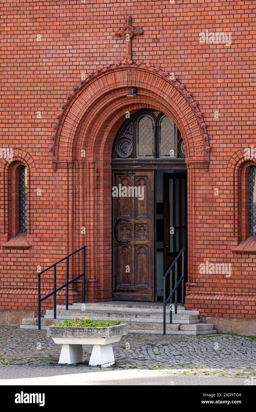 Ingresso alla chiesa in mattoni con porta ornata e croce Foto Stock